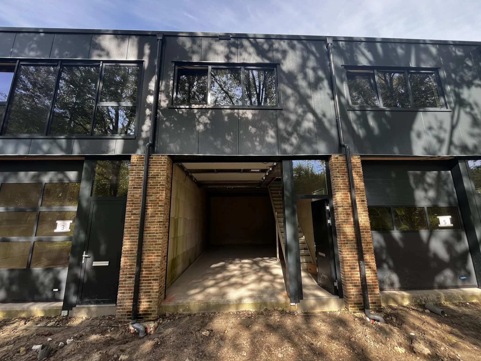 Voorgevel van een modern bedrijfsgebouw aan de Broekdijk-West met deunits 3, 4 en 5 en een openstaande garagedeur.